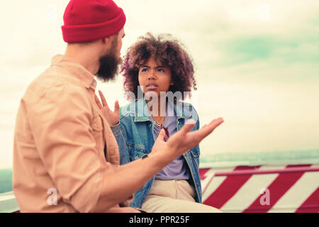 Young couple using gestures while having serious talk Stock Photo