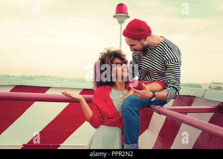 Happy man sitting on the hand rail and laughing with girlfriend Stock Photo