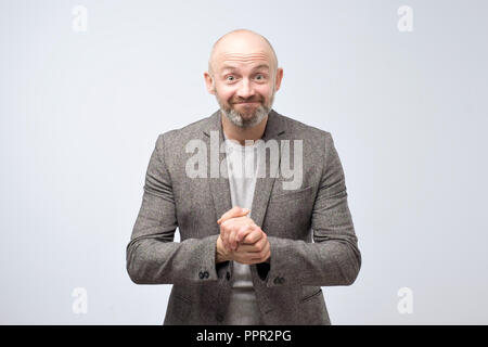 Positive mature man rubs his hands, rejoicing at a successful deal Stock Photo