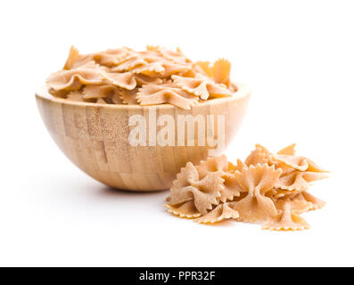Wholewheat farfalle pasta. Tasty italian pasta in wooden bowl isolated on white background. Stock Photo