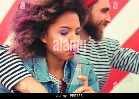 Young girl closing her eyes and drinking from the sipping straw Stock Photo