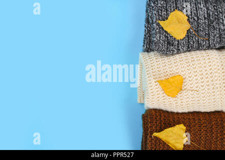 Warm knitted sweaters. Pile of knitted clothes on blue background, sweaters, knitwear, space for text, Autumn winter concept. Top view Stock Photo