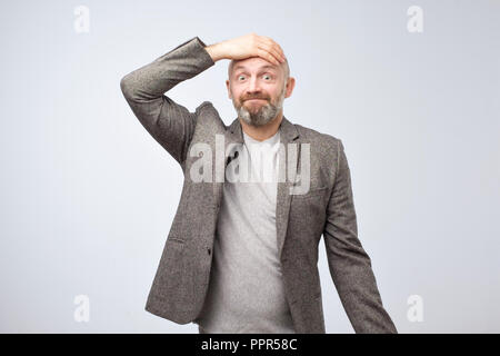 Closeup portrait of a man holding his hand on head, staring thoughtfully at camera Stock Photo