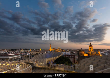Elevated view of Seville rooftops at dusk as seen from the Metropol Parasol on Plaza de la Encarnacion, with the illuminated Cathedral and other churc Stock Photo