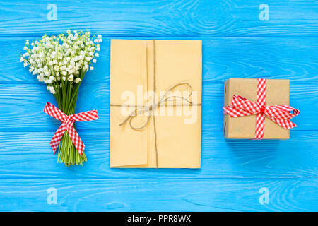 Spring blue background with bouquet and envelope, gift box, top view, copy space for text, flat lay Stock Photo