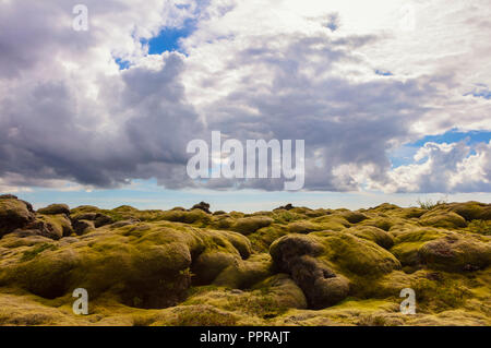 A cloudy sky and the ancient lava field, covered with moss near Vik, Iceland, seen from the famous Ring Road that is well traveled by tourists. Stock Photo