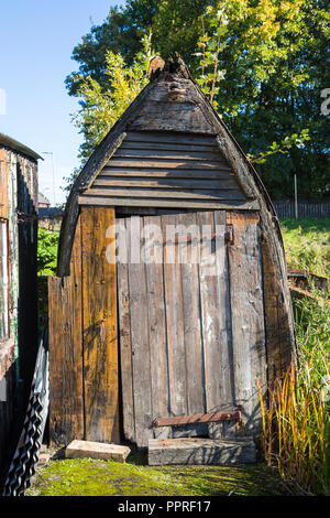 Old canal boat upturned and used as a outside store shed or toilet Stock Photo