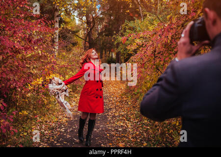 Man takes a picture of his girlfriend dancing using camera in autumn forest Stock Photo