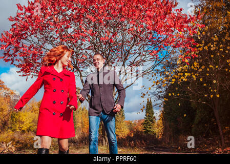 Young couple in love runs in autumn forest among colorful trees. Happy people having fun Stock Photo