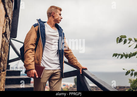 College student with backpack and book admiring sea landscape view in Odessa walking in city on rainy day Stock Photo