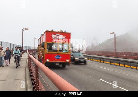 Pedestrians, bikers and a tour bus on the Golden Gate Bridge San Francisco, California, United States, on a late foggy summer morning. Stock Photo