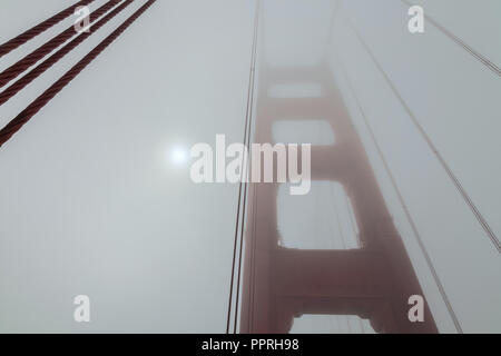 Morning sun is shining through the thick fog at the Golden Gate Bridge on a  late summer day, San Francisco, California, United States Stock Photo