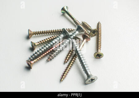 A pile of wood screws and screwdriver shaft head closeup on white background Stock Photo