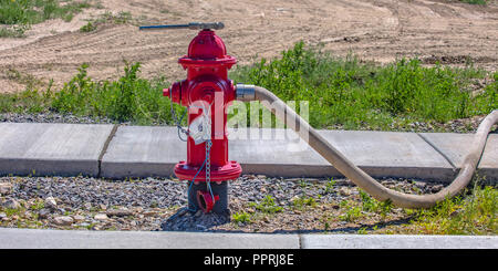 Fire pump with wrench on top and hose on nozzle Stock Photo