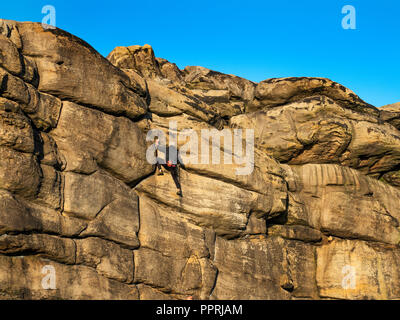 Rock climber at Almscliff Crag millstone grit outcrop near Harrogate North Yorkshire England Stock Photo