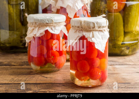 Homemade canned vegetables in cans. Pickled tomatoes and cucumbers in a rural style Stock Photo