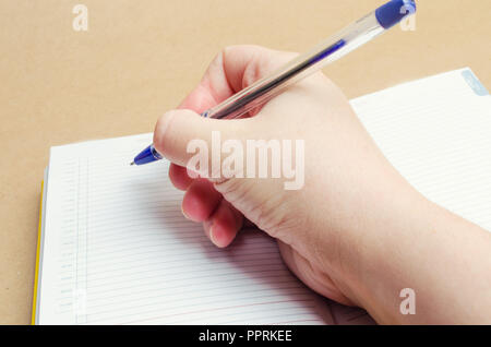 a female hand writes in a notebook and makes notes, plans for the day, shopping list, close-up, businessman makes notes on the calendar, concept schoo Stock Photo