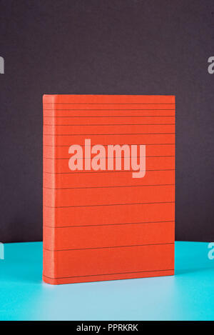 Red striped book on the green metal table. Black background. Stock Photo