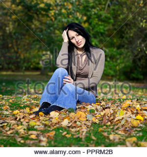 Woman sitting in the park and enjoying the Autumn sunshine Stock Photo