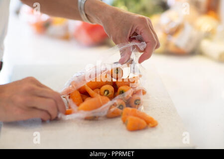 Unpacking plastic wrapped fruit and vegetables in the kitchen - Plastic packaging on fruit and vegetables in the UK Stock Photo