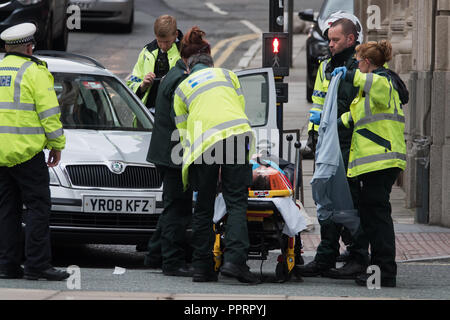 Ambulance paramedics and police officers help an injured man on a stretcher after a car crash. Stock Photo