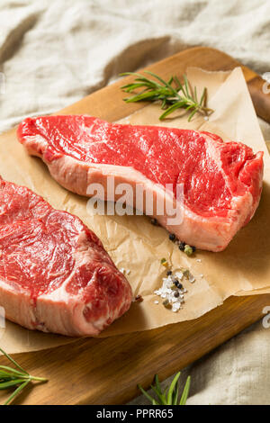 Raw Grass Fed NY Strip Steaks with Salt and Pepper Stock Photo
