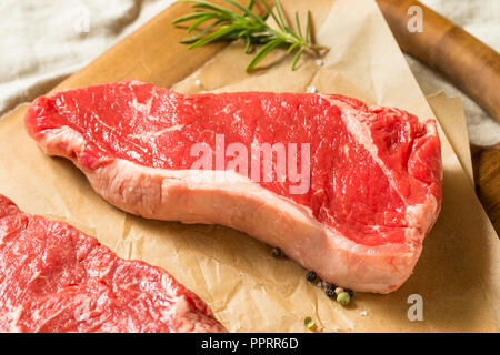 Raw Grass Fed NY Strip Steaks with Salt and Pepper Stock Photo