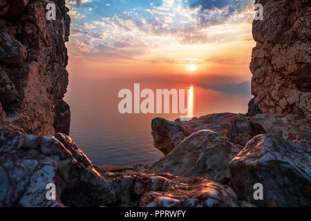 View of sunset on sea view through window in fortress with reflection on stones and shape sun rays clouds. Holiday vacation travel seascape Toned land Stock Photo