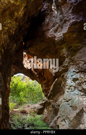 View to small tunnel in big hard rock leading to green forest in Cerro del Hierro, Seviile Stock Photo