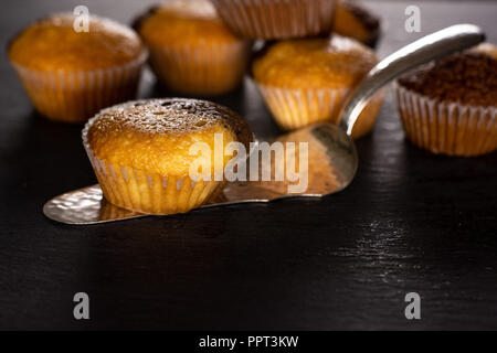 Lot of whole fresh baked marble muffin on silver cake server on grey stone Stock Photo