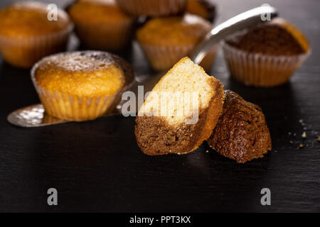 Group of lot of whole two halves of fresh baked marble muffin on silver cake server on grey stone Stock Photo