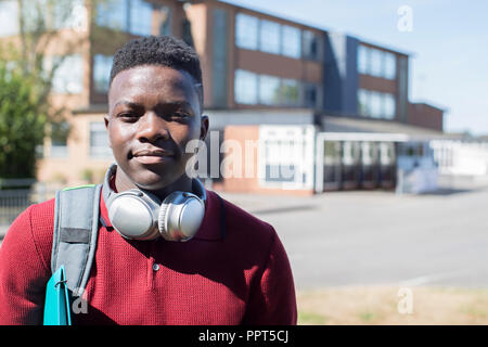 Portrait Of Male Teenage Student Outside College Building Wearing Wireless Headphones Stock Photo