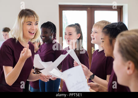 Children In School Choir Being Encouraged By Teacher Stock Photo