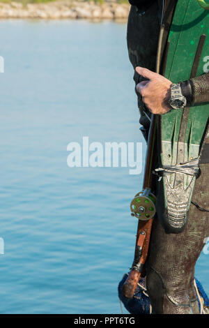 Crop view of scuba diver adult man on a seashore with spearfishing