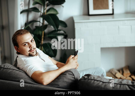 Handsome man is sitting on the sofa at home Stock Photo