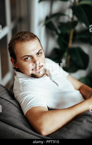 Handsome man is sitting on the sofa at home Stock Photo