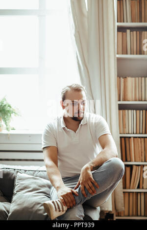 Handsome man is sitting on the sofa at home Stock Photo