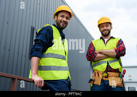 two architects in safety vests and hardhats standing on construction Stock Photo