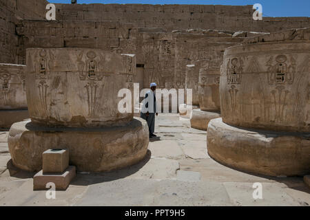 Egyptian man walking across courtyard of cut-off columns in Medinet Habu Temple of Ramses III in Luxor, Egypt. Stock Photo