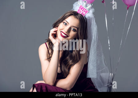 https://l450v.alamy.com/450v/ppta13/smiling-future-bride-in-veil-for-bachelorette-party-sitting-on-chair-with-tied-pink-balloons-isolated-on-grey-ppta13.jpg