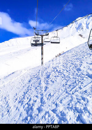 Chairlift cable car and ski slopes in the mountains of winter resort in French Alps Stock Photo