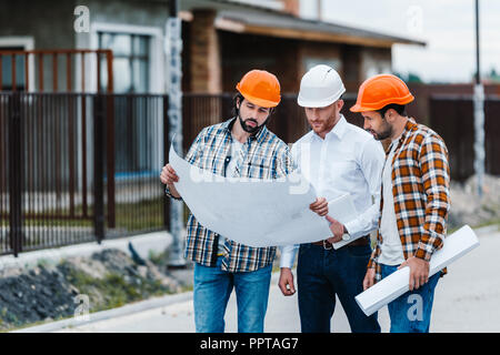 group of architects standing on building street with blueprints Stock Photo