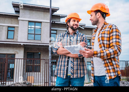 happy architects using digital tablet at construction site Stock Photo