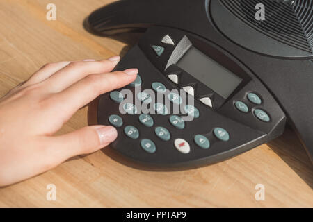 cropped shot of businesswoman pushing button of speakerphone on table at office Stock Photo