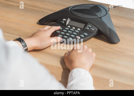 cropped shot of businesswoman pushing button of conference phone on table at office Stock Photo