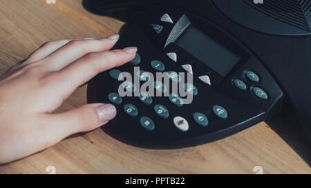 cropped shot of businesswoman pushing button of speakerphone on table at office Stock Photo