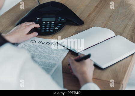 cropped shot of businesswoman with contract pushing button of conference phone on table at office Stock Photo