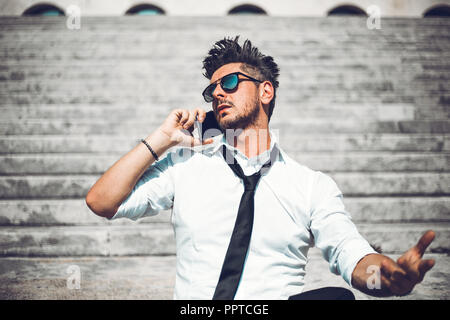 Depressed unsuccessful businessman feels terrible headache, hands shocked by bankruptcy stock downfall sitting on stone stairs. Stressed tired man fee Stock Photo