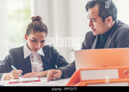 Two analysts discussing online data in front of laptop Stock Photo