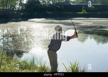 A fisherman catches a fish. Hands of a fisherman with a spinning rod in  hand closeup. Spin fishing reel Stock Photo - Alamy